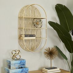 a gold shelf with books on it next to a potted plant and other items