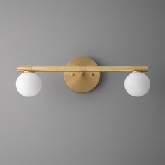 two white balls are on the wall next to a light fixture that is attached to a gray wall