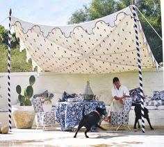 a man sitting on a couch next to a black dog in front of a tent