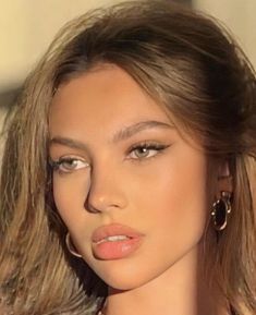 a close up of a woman with long hair and earrings on her head, wearing gold jewelry