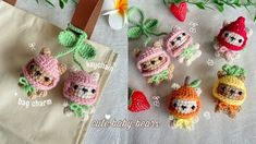 small crocheted stuffed animals sitting next to each other on a table with strawberries and flowers