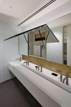 a bathroom with two sinks, mirrors and lights on the wall above them is shown