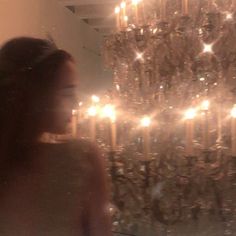 a woman standing in front of a chandelier