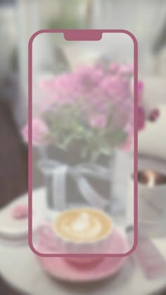 a pink phone case sitting on top of a table next to a cup of coffee