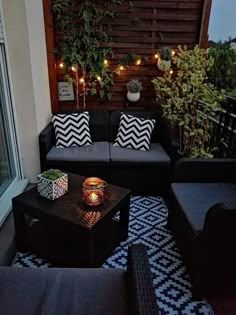 an outdoor living area with couches, tables and lights