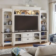 a living room with white furniture and a flat screen tv on top of a entertainment center