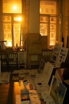 the room is full of art work and papers on the floor in front of windows