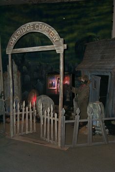 an outdoor display with people standing in front of a small wooden structure and fenced off area