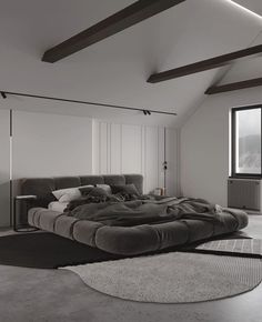 a large bed sitting in the middle of a room next to a window and rug