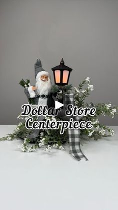 a santa clause doll sitting on top of a table next to a lantern and flowers