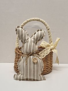 a small basket with a stuffed bunny in it and a ribbon tied around the handle