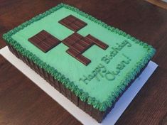 a cake that is sitting on top of a table with green frosting and chocolate decorations