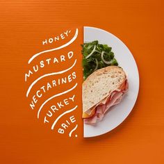 a white plate topped with a cut in half sandwich next to a green salad on an orange background