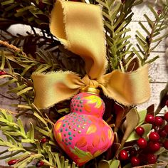 an ornament is hanging from a christmas tree with berries and pine cones on it