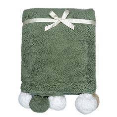 a green towel with pom poms on the bottom and white ribbon around it