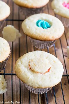 several muffins with icing and sprinkles on a cooling rack