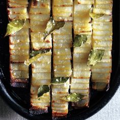 sliced up food in a black pan on top of a white tablecloth and cloth