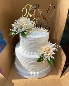 a wedding cake in a box with flowers on top