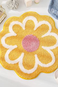 a yellow flower rug sitting on top of a white table next to towels and slippers