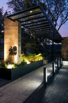 the entrance to an apartment building with lights on it's sides and trees in the background