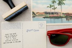 a pair of red sunglasses sitting on top of a table next to a postcard