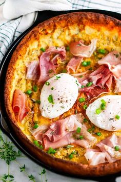 an omelet with ham and eggs in a skillet on a white table