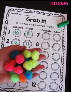 a hand holding some colored pom poms in front of a printable game