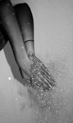 a black and white photo of someone's hand in the bathtub with glitter on it