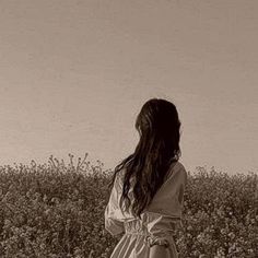 a woman standing in a field looking at the sky