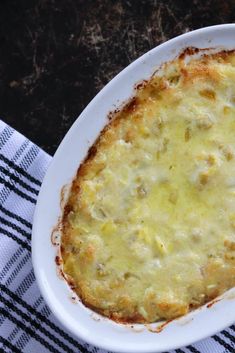 a casserole dish with cheese and meat in it on a blue and white checkered table cloth