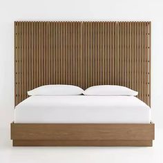 a bed with white sheets and pillows in front of a wooden headboard that has bamboo slats on it