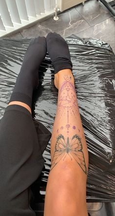 a person with tattoos on their legs sitting in front of a black sheet covered floor