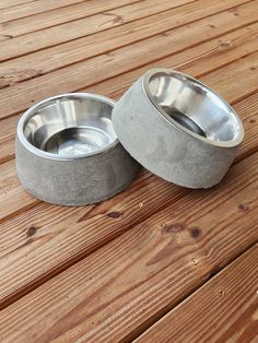 two metal bowls sitting on top of a wooden table