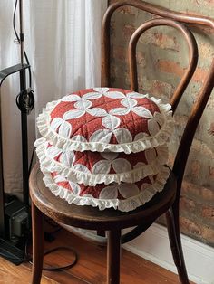 a stack of pillows sitting on top of a wooden chair next to a brick wall