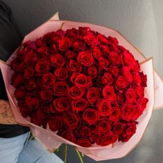 a person holding a large bouquet of red roses in their left hand and wearing a black shirt