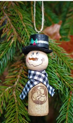 a christmas ornament hanging from a tree with a snowman on it's head