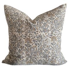 a white and blue floral pillow on a white background