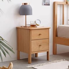 a bedroom scene with focus on the bedside table and bed in the foreground, along with a potted plant