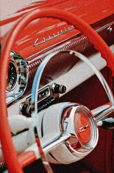 the steering wheel and dashboard of an old classic car with red dash lights on it