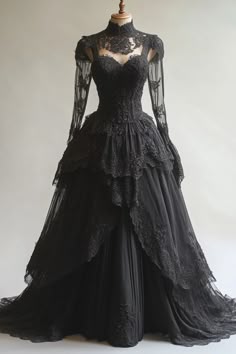 a black dress with sheer sleeves and lace on the top, is displayed in front of a