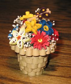 a basket filled with lots of different colored flowers on top of a wooden table next to scissors