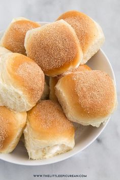 a white plate filled with rolls covered in sugar on top of a marble countertop