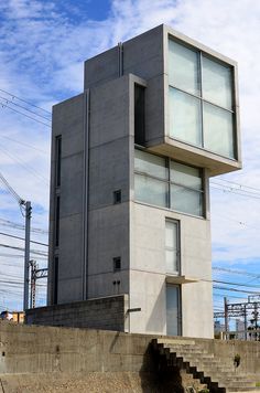 a concrete building with stairs leading up to it's second story and windows on the top floor