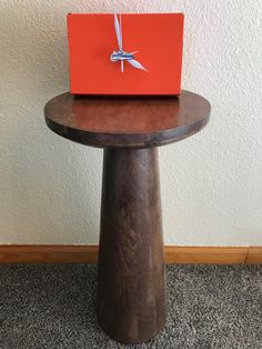 an orange box sitting on top of a wooden table in front of a white wall