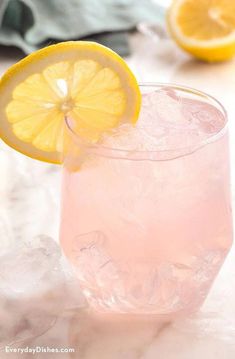 a close up of a drink on a table with lemons and ice cubes