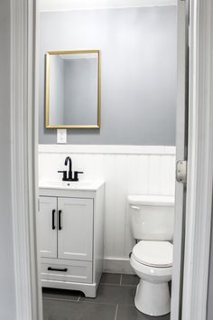 a white toilet sitting next to a sink in a bathroom under a mirror on the wall