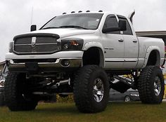 a large white truck parked on top of a grass covered field next to a building