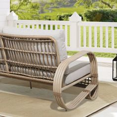 a wicker couch sitting on top of a rug next to a white picket fence