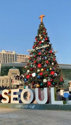 a large christmas tree in front of the seoul sign