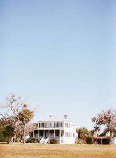 a large white house sitting on top of a lush green field under a blue sky